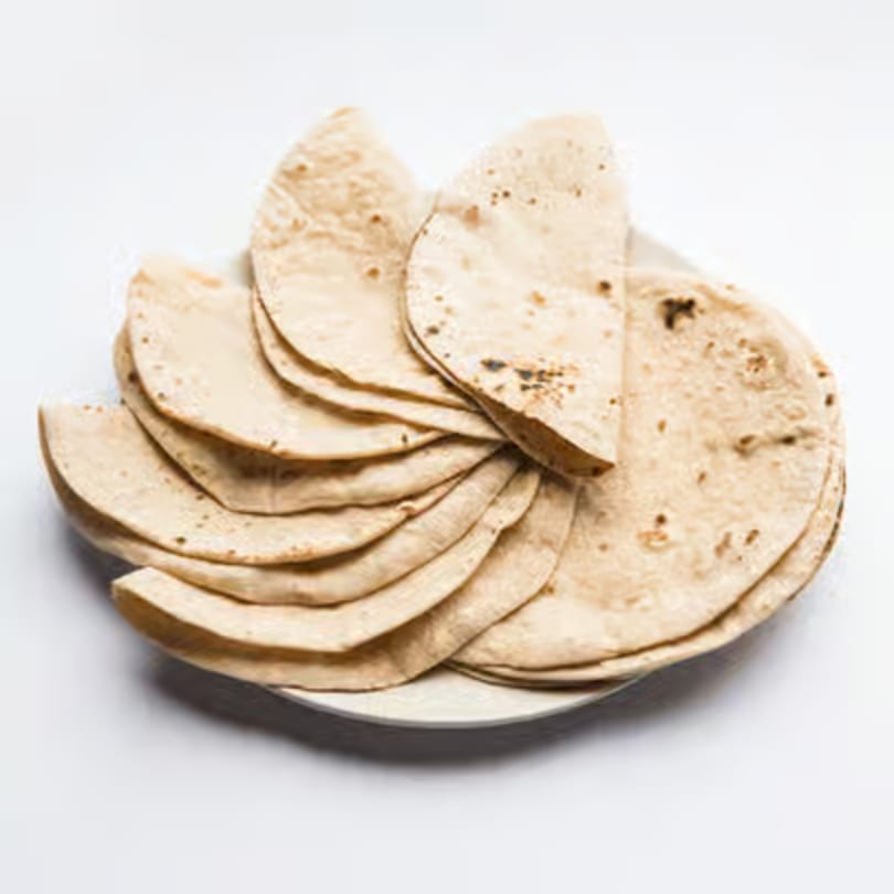 A plate of freshly made, folded Indian flatbreads, likely rotis or chapatis, on a white background.