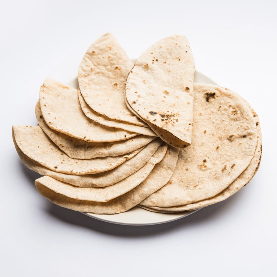A plate piled high with freshly made, warm Indian flatbread, known as roti or chapati.
