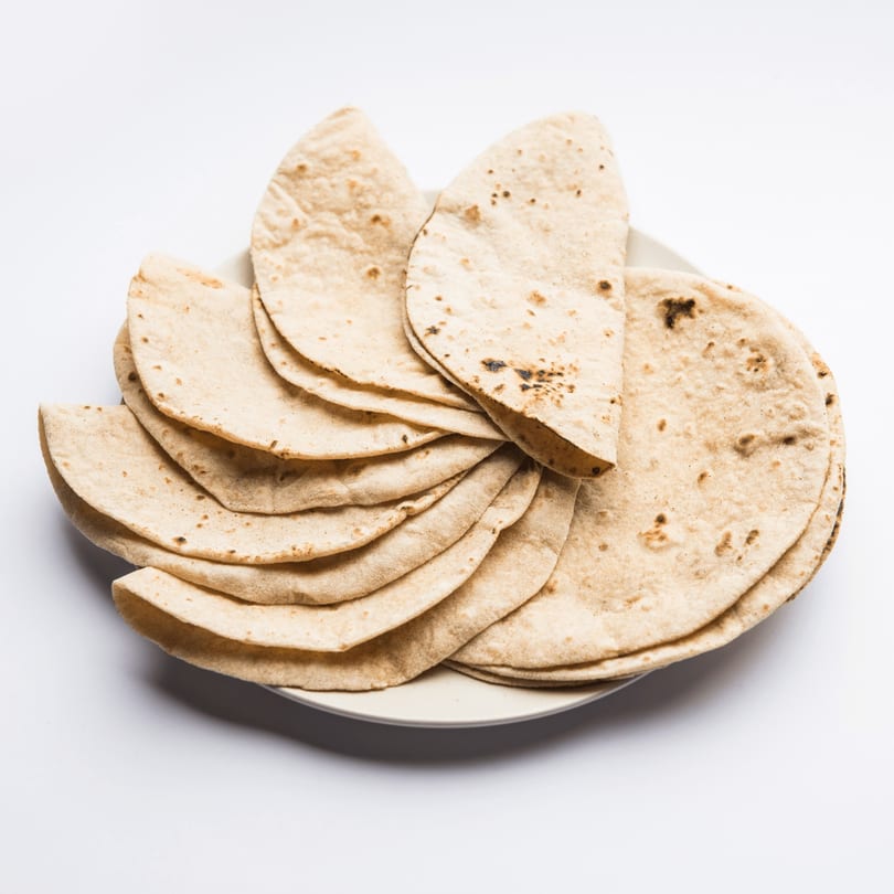 A plate piled high with freshly made, warm Indian flatbread, known as roti or chapati.
